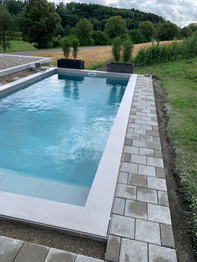 Fertiger Pool mit gepflastertem Rand im Garten