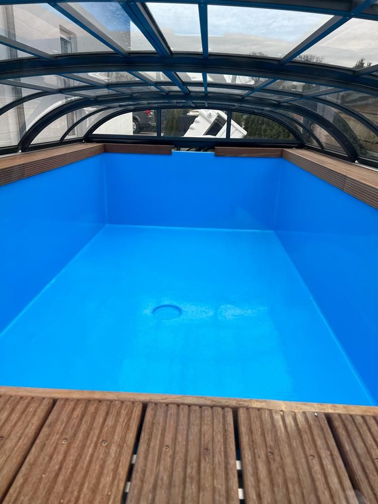 Fertig beschichtetes Pool-Becken unter einer Überdachung mit Holzdeck